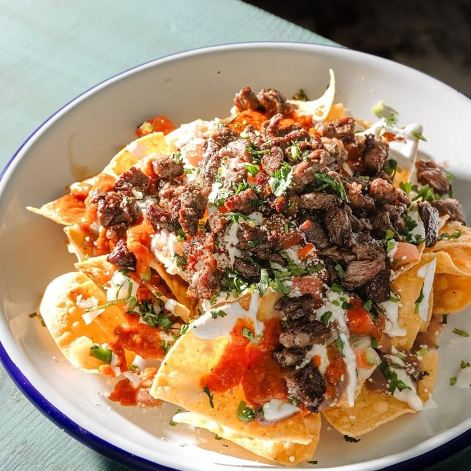 A large plate of Blue Rabbit Bar's loaded nachos with steak, cheese, salsa, and sour cream.