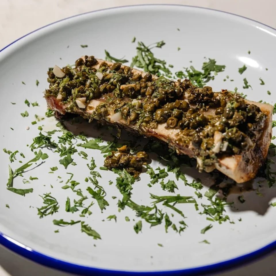 A Blue Rabbit Bar dish featuring a large piece of bone marrow topped with capers and herbs.